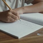 eleve assis ecrit calcul sur cahier ouvert