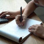 Eleve assis ecrivant sur copie double avec calculatrice