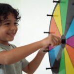 enfant souriant tournant une grande roue colorée