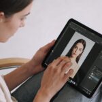 Jeune graphiste assis retouchant une photo sur tablette