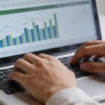 mains tapant sur clavier devant ecran montrant graphique excel