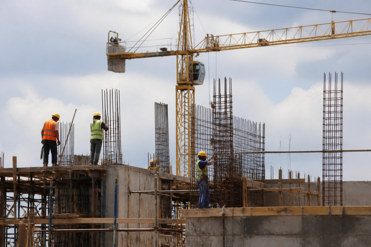 Chantier de construction avec ouvriers casques et grue jaune