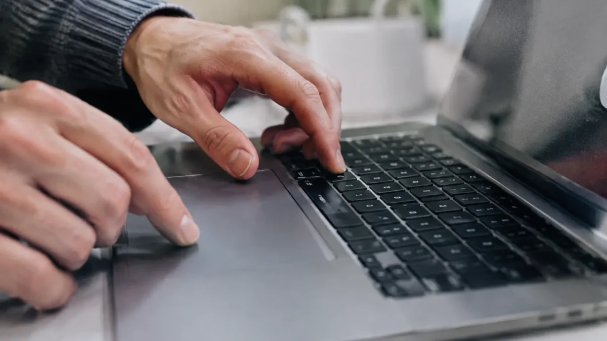 Doigts pressant deux touches sur un ordinateur portable gris