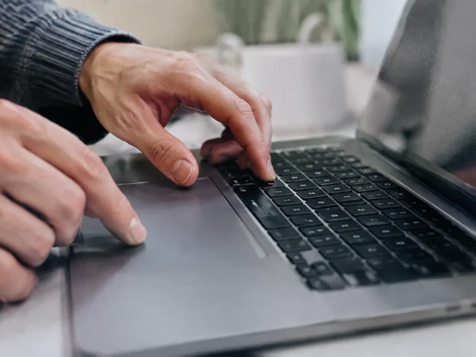Doigts pressant deux touches sur un ordinateur portable gris