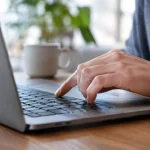 Main appuyant sur une touche du clavier portable