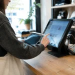 Main pressant un ecran tactile sur comptoir de magasin
