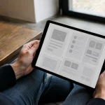 Mains tenant une tablette affichant une maquette de wireframe