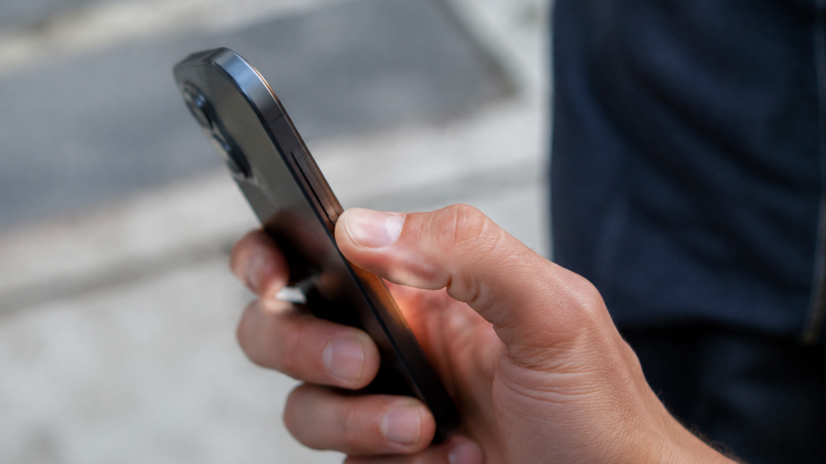 Un pouce appuie sur le bouton lateral du smartphone