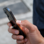 Un pouce appuie sur le bouton lateral du smartphone