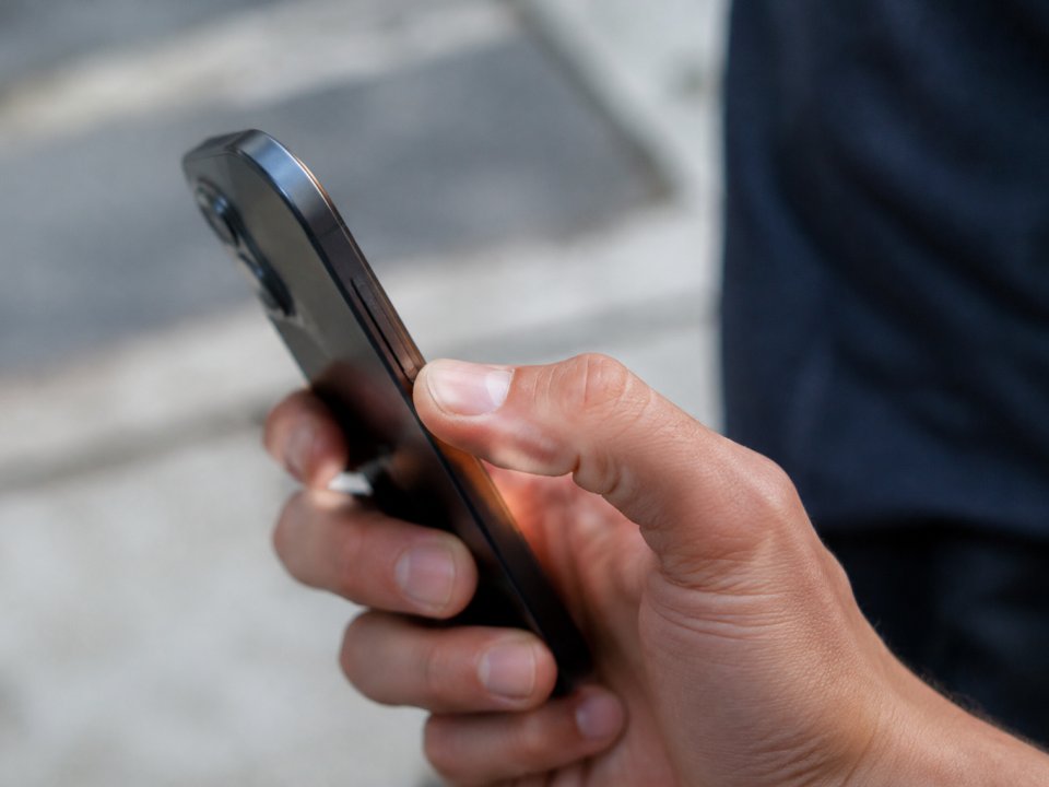 Un pouce appuie sur le bouton lateral du smartphone