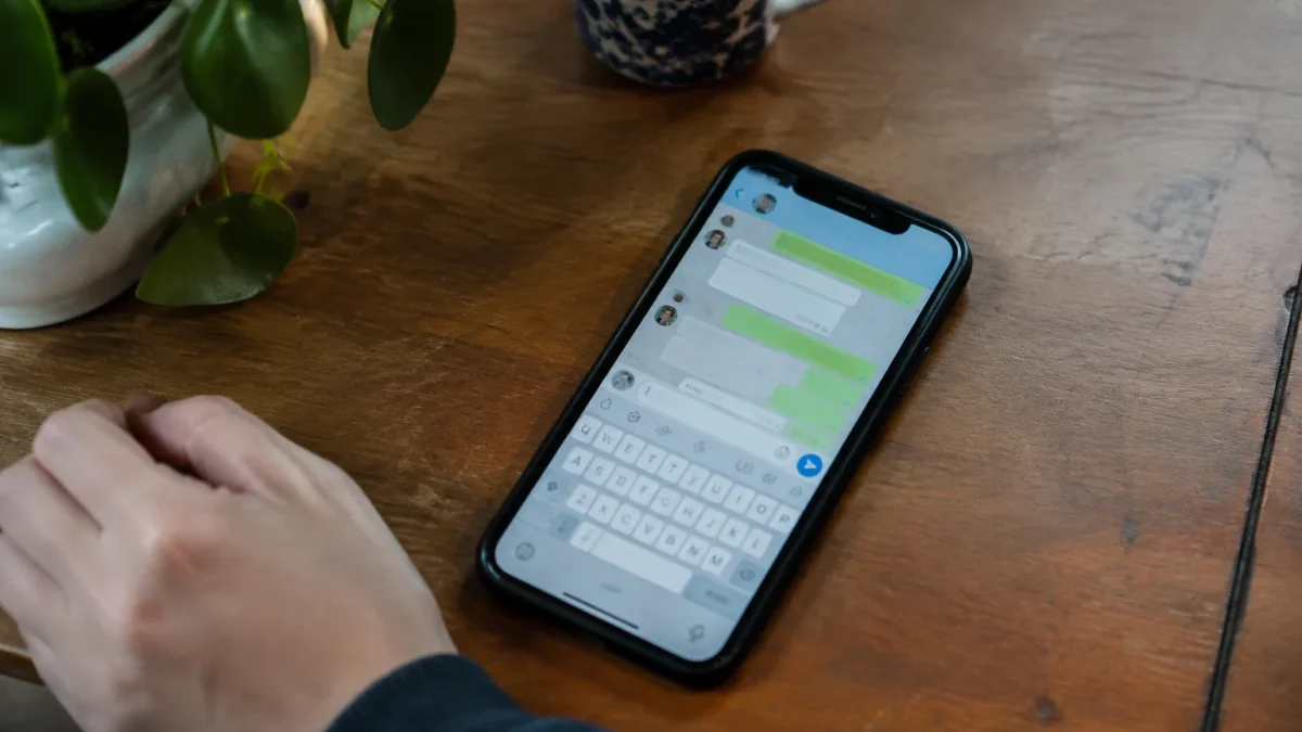 Smartphone pose sur table, ecran affichant une messagerie ouverte