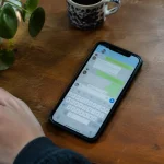 Smartphone pose sur table, ecran affichant une messagerie ouverte
